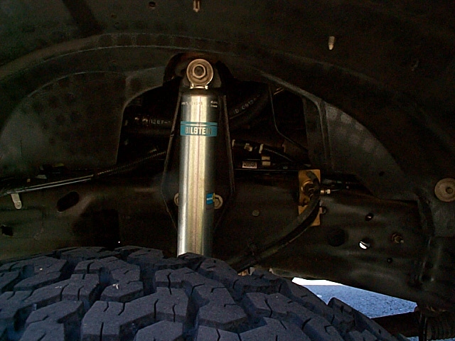 Bilstein shock absorber mounted under a vehicle above a mud-terrain tire
