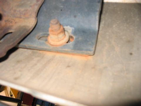 1988 Ford Bronco - A rusted bolt is visible in a metal bracket, against a textured background.