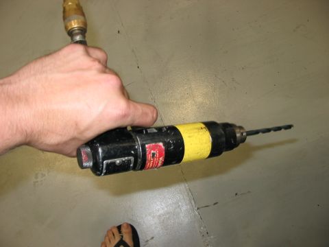 1988 Ford Bronco - A hand holds a black and yellow drill with a drill bit attached, ready for use.