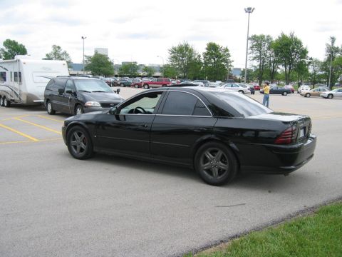 2000 Ford Crown Victoria - Three-quarter rear view of a black Lincoln LS sedan with heavily tinted windows, dark-finished five-spoke alloy wheels and smoked tail ligh…