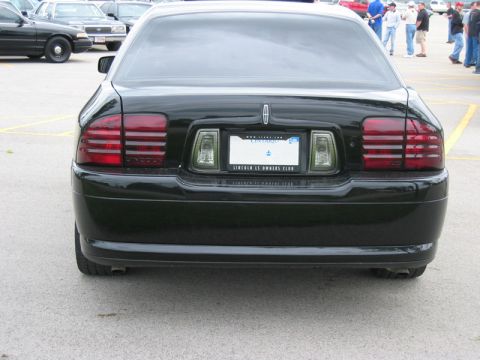 2000 Ford Crown Victoria - Straight-on rear view of a black Lincoln LS sedan on a paved lot, showing the slatted taillights, Lincoln star badge on the trunk, and an O…
