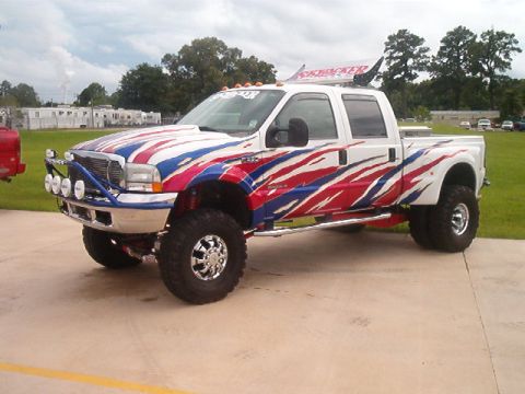 1980 Ford Bronco - This lifted pickup truck features a patriotic red, white, and blue flame graphic design and a "SkyJacker" banner on the roof.