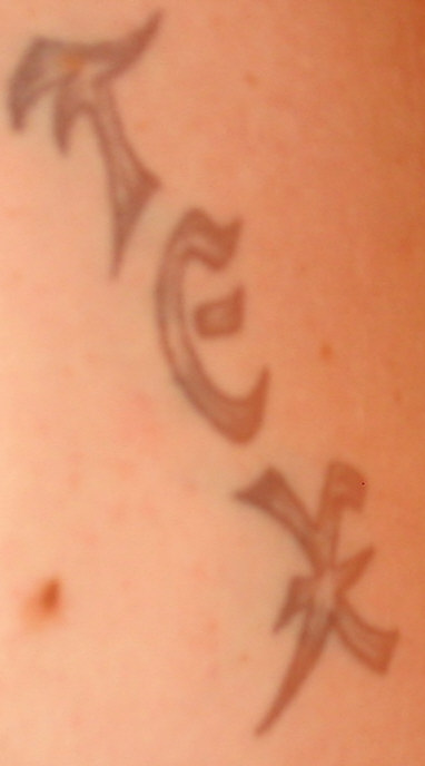 1988 Ford Bronco - A close-up of a tattoo with stylized characters on a person's skin.
