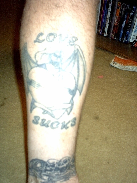 1995 Ford Bronco - A tattoo on a person's leg reads 'LOVE SUCKS' above a winged heart design.