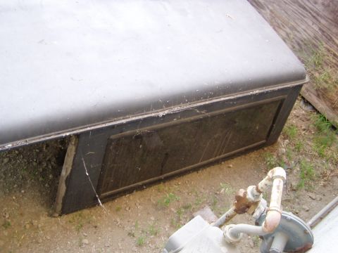 1967 Ford Bronco - A dark truck cap rests on the ground, showing a framed window on its side.
