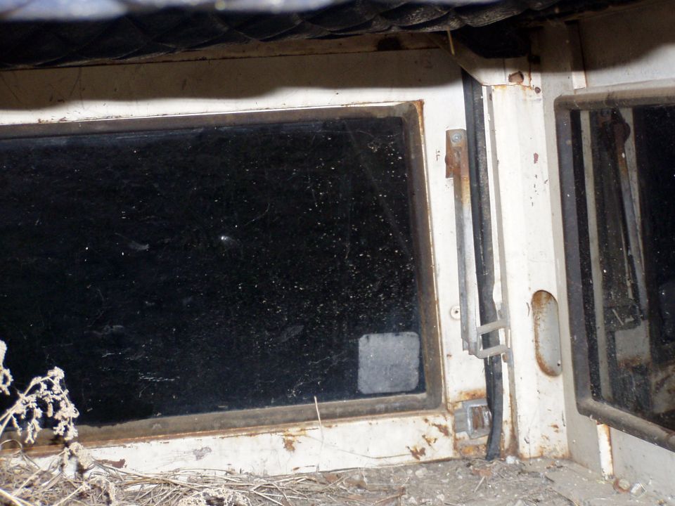 Close-up of a white vehicle door frame with a dirty, scratched window and a partially open door