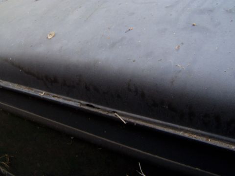 1967 Ford Bronco - Close-up view of a dark-colored vehicle's body panel, revealing rust and wear along a seam.