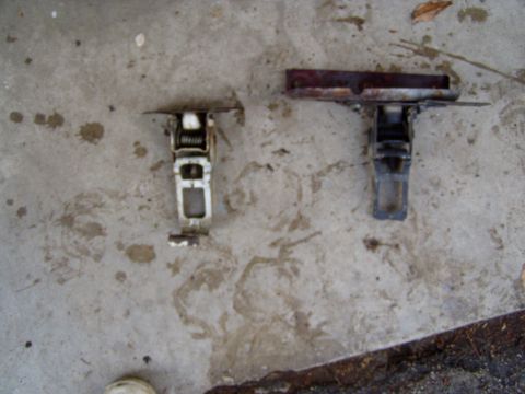 1967 Ford Bronco - Two car hood latches are shown lying on a concrete surface.