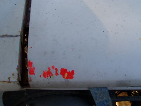 1967 Ford Bronco - Close-up view of chipped and peeling paint on a vehicle's body, revealing rust underneath.