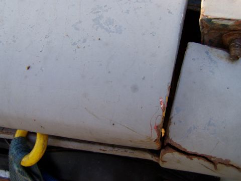 1967 Ford Bronco - Detail of a corroded seam on a vehicle part, showing rust and a yellow lifting strap.