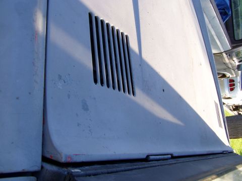 1967 Ford Bronco - A portion of a vehicle's fender with a vent is shown, with other vehicles visible in the background.