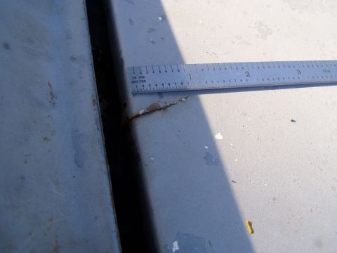 1967 Ford Bronco - Ruler shows gap measurement on gray metal panels, one panel has a crack.