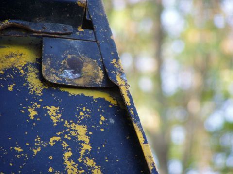 1967 Ford Bronco - The weathered surface of a metal part shows significant wear and tear with chipped paint and rust.
