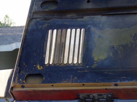 1967 Ford Bronco - Close-up of a vehicle's hood vent, chrome slats against a weathered dark blue finish.