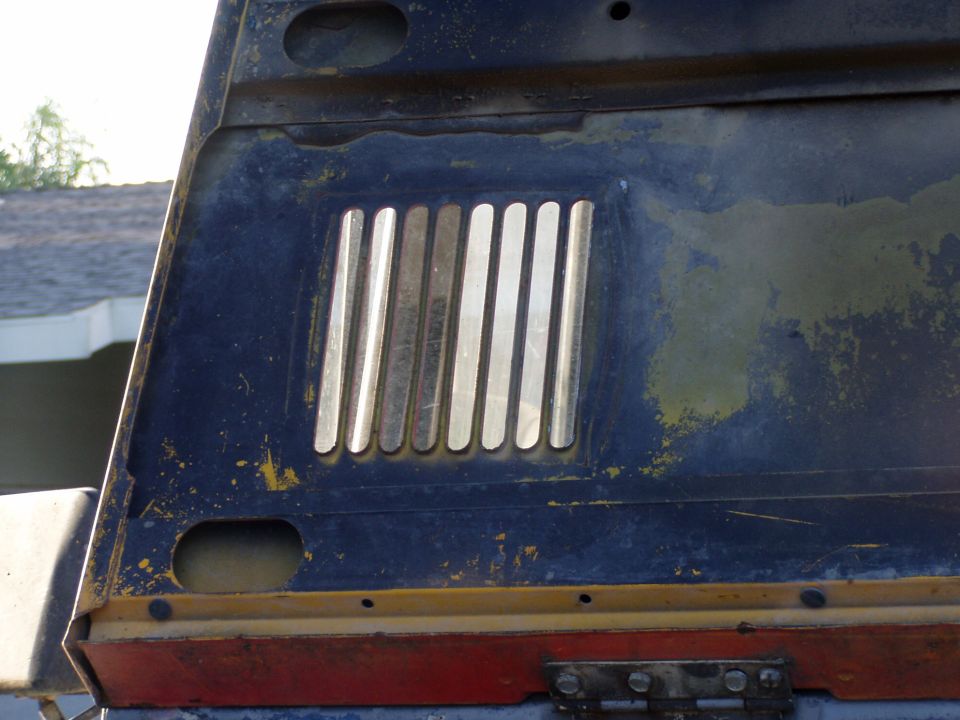 Hood vent with chrome slats on a dark blue surface