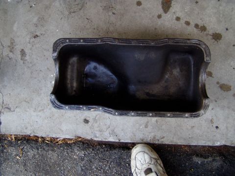 1967 Ford Bronco - Oil pan on concrete, with a shoe visible in the lower right corner.