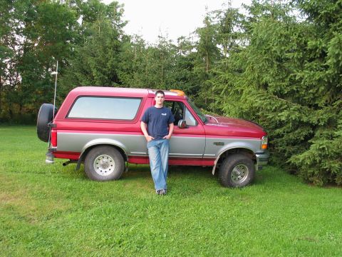 1995 Ford Bronco - A man poses with his 1995 Ford Bronco parked on a grassy lawn with trees in the background.