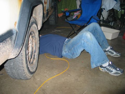 1995 Ford Bronco - Someone is working on a vehicle, lying on the floor near the wheel.