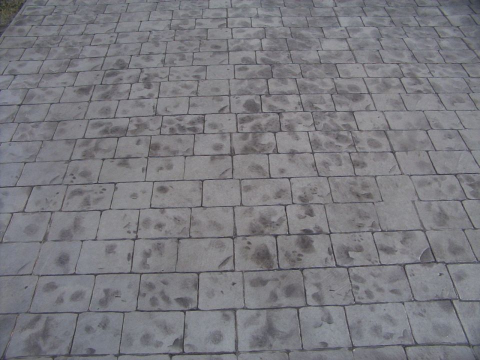 Stamped concrete patio with dark stains, viewed from a high angle