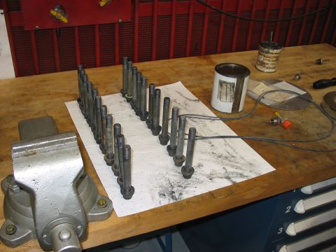 1988 Ford Bronco - Bolts are laid out on a workbench next to a vise and a can of lubricant.
