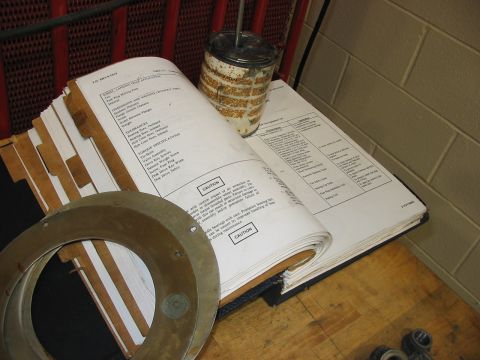 1988 Ford Bronco - A service manual and a can of parts are laid out on a wooden surface.