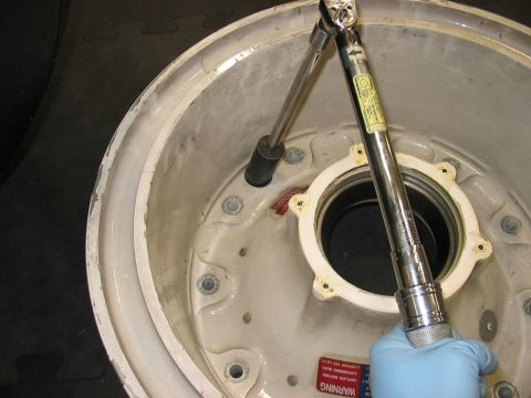 1988 Ford Bronco - A torque wrench is used to tighten lug nuts on a wheel hub, indicating a part of a vehicle is being serviced.