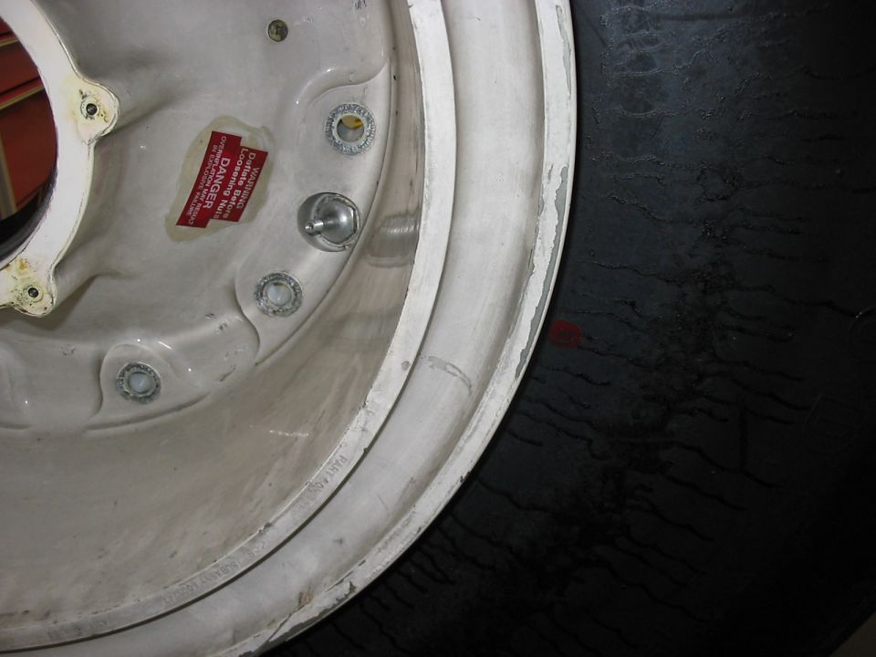Close-up of a vehicle wheel rim with a red DANGER sticker and lug nut holes