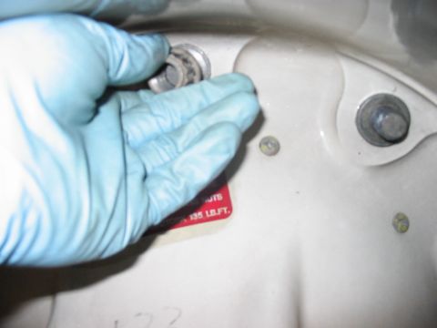 1988 Ford Bronco - Close-up of a hand in a glove working on a bolt, with a sticker indicating torque specifications.