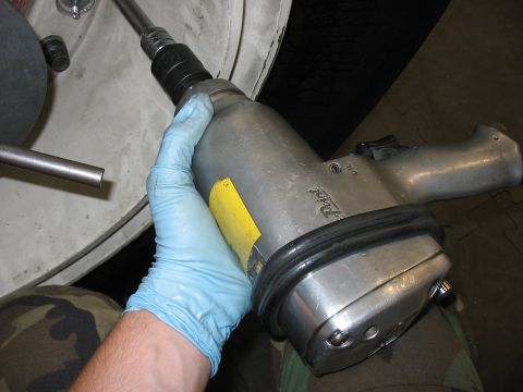1988 Ford Bronco - A blue-gloved hand grips a silver impact wrench, positioned near a tire rim.