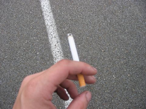 1988 Ford Bronco - A person holds a lit cigarette over a paved surface marked with a white line.