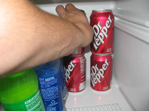 1988 Ford Bronco - A hand reaches for Dr Pepper cans stored in a refrigerator alongside other beverages.