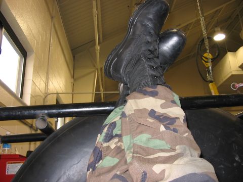 1988 Ford Bronco - A person wearing camouflage pants and black combat boots is seen with their legs propped up indoors.