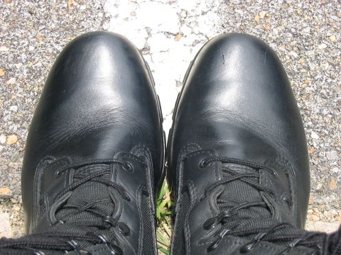 1988 Ford Bronco - A close-up view of two black leather boots resting on a surface with gravel and white markings.