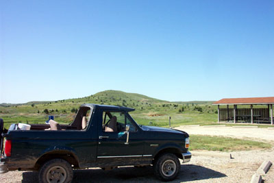 1995 Ford Bronco - A dark green 1995 Ford Bronco with its top removed sits parked in a scenic outdoor location.