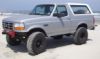 1995 Ford Bronco - This 1995 Ford Bronco is captured in a three-quarter front view, parked on a sandy beach with the ocean in the background.