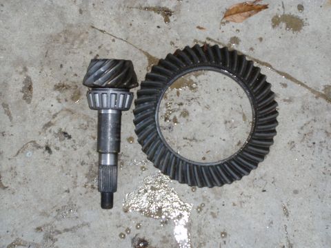 1985 Ford Bronco - A set of differential gears, including a pinion and ring gear, are shown on a concrete surface.