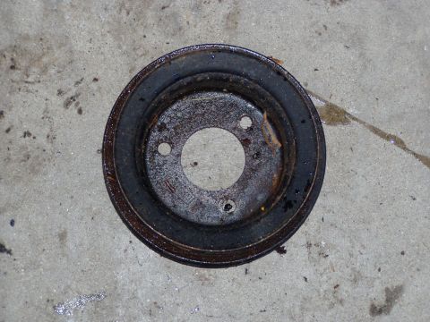 1967 Ford Bronco - This rusty pulley is a replacement part for a vehicle, but its specific make and model are not identifiable from the image.
