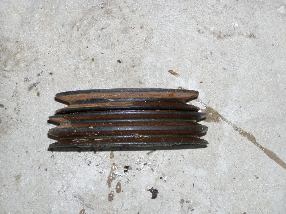 Rusty three-groove cast-iron V-belt pulley lying on a concrete floor