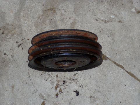 1967 Ford Bronco - A rusty, two-groove pulley sits on a concrete surface, showing signs of wear and tear.