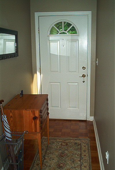 1985 Ford LTD Crown Victoria - Entryway scene a white door with arched glass, a wooden chest, and an umbrella stand.