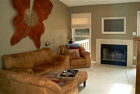 Living room with tan leather sofa, armchair, ottoman with tray, and fireplace