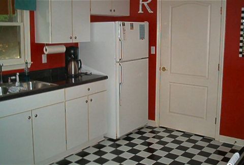 1985 Ford LTD Crown Victoria - A kitchen scene white cabinets, a black countertop, and a checkered floor.