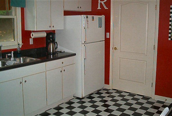 Kitchen scene with white cabinets, black countertop, stainless steel sink, and a white refrigerator