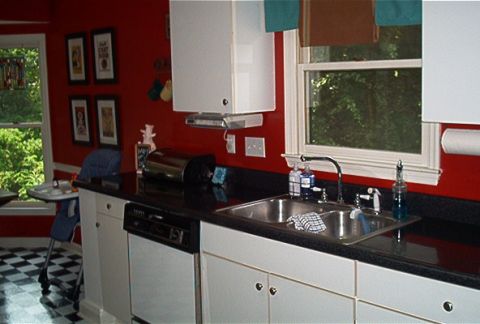 1985 Ford LTD Crown Victoria - A view of a kitchen with red walls, black countertops, and a double sink.