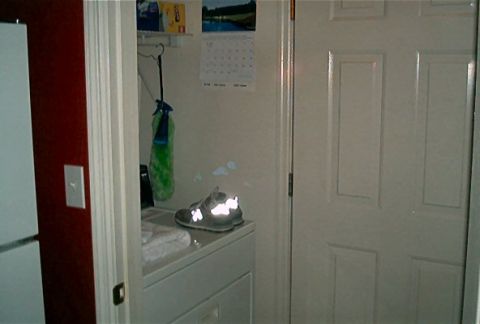 1985 Ford LTD Crown Victoria - A shoe rests on top of a washing machine in a room with a calendar on the wall.
