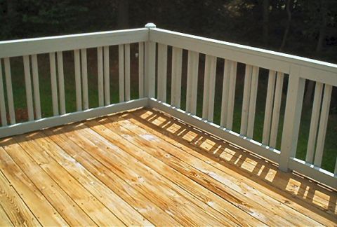 1985 Ford LTD Crown Victoria - A view of a wooden deck and its white railing, with sunlight casting shadows on the planks.