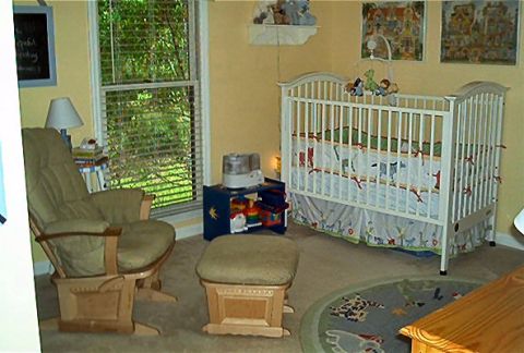1985 Ford LTD Crown Victoria - A nursery room features a crib with animal bedding, a comfortable glider chair, and a round rug on the floor.