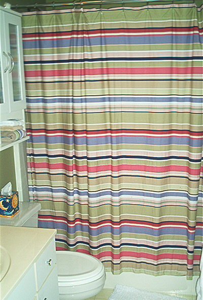 1985 Ford LTD Crown Victoria - A bathroom scene includes a toilet, vanity, and a colorful striped shower curtain.