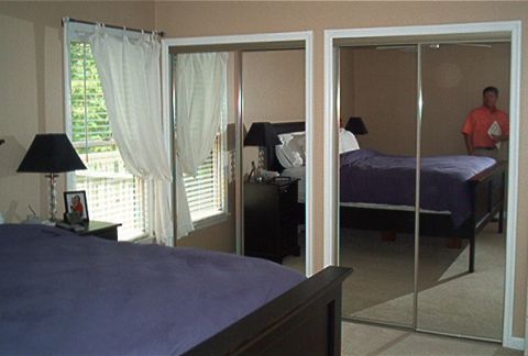 1985 Ford LTD Crown Victoria - A bedroom scene is reflected in mirrored closet doors, showing a bed and a man standing in the room.