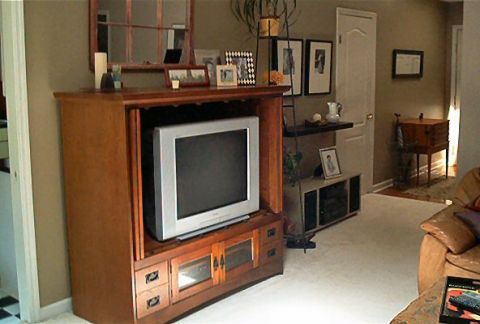 1985 Ford LTD Crown Victoria - A living room scene a television set within a wooden entertainment unit, surrounded by decorative items and furniture.
